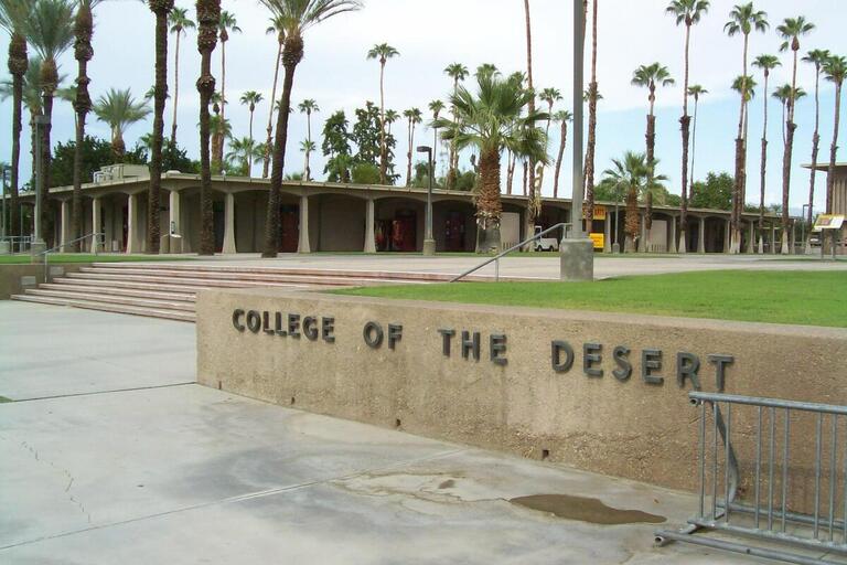 a landmark sign/wall with the text "college of the desert". the wall circles a raised lawn
